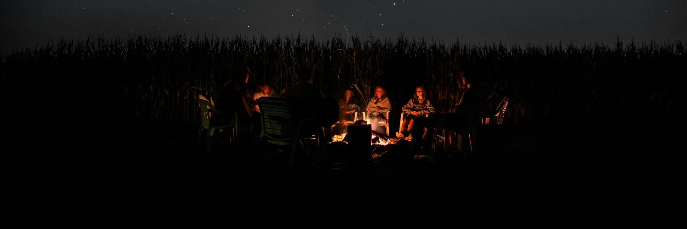 Campers gathered around a campfire at night