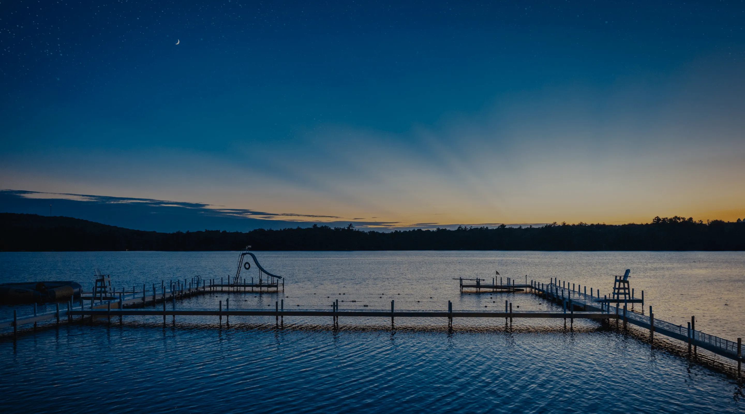 Sunrise over a calm lake and wooden jetty at an American summer camp
